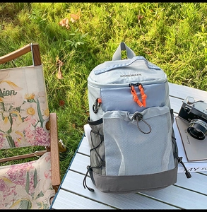 Sac à dos de loisirs en nylon bleu clair et gris posé sur une table de camping en métal