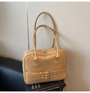 Detailed view of khaki leather tote bag with three decorative buckle straps and silver zipper