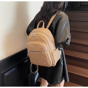 Woman wearing camel leather backpack showing back view in casual indoor setting