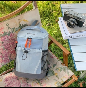 Détail d'un sac à dos extérieur bleu clair avec fermetures orange sur une table de camping
