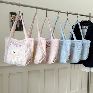 Detail of heart-quilted tote bags in pink and blue featuring cute puppy embroidery