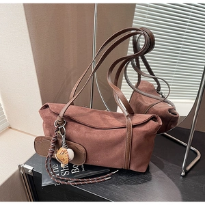 Gros plan du sac porté épaule en daim marron avec charm de baseball et petite pochette