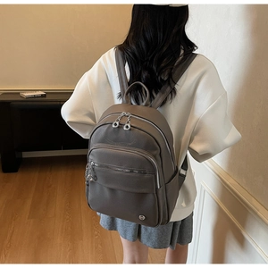 Detail of dark grey textured faux leather backpack showing the side pockets and silver zippers