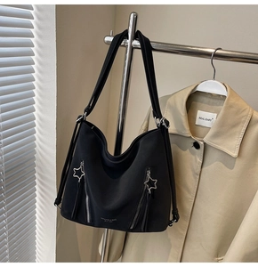 Detail of black tote bag with star-shaped zippers and brand logo on nylon fabric