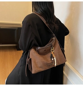 Detail of brown faux suede tote bag featuring ethnic beads and a metal logo plaque