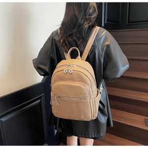 Lifestyle view of a light brown pebble grain leather backpack worn on model's back