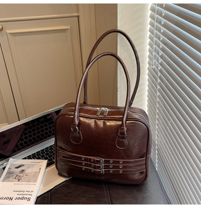 Detail of dark brown tote bag with metal eyelet straps on a leather bench setup