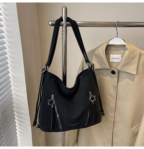 Detail of black tote bag with star shaped metal zippers and brand logo on bottom