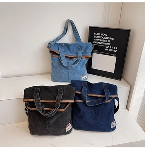 Detailed view of denim tote bags with leather trim and woven handles in three colors