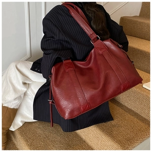 Macro detail of wine red PU leather tote with reinforced stitching on the long handle straps