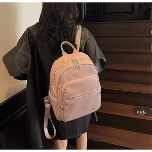 Pink pebbled faux leather backpack worn on stairs showing size and delicate texture