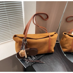 Détail d'un sac hobo en daim caramel avec breloque tissée et bandoulière en cuir