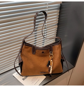 Detail of brown suede tote bag featuring deep leather piping and white stitching