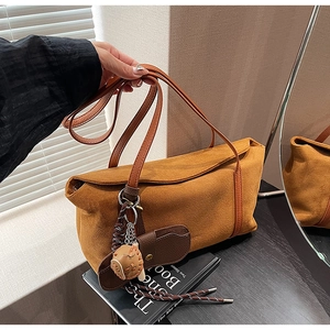 Détail du grand sac cabas en daim marron avec bandoulière et pendentif gant de baseball