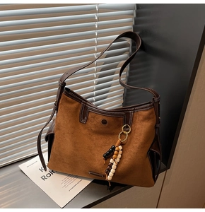 Detailed close-up of brown suede tote bag with leather straps and decorative wooden beads