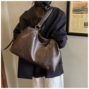 Detail of deep brown faux leather tote bag with cross-stitch shoulder strap reinforcement
