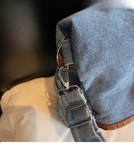 Detail of blue denim bucket bag with silver metal hooks and brown leather piping edges