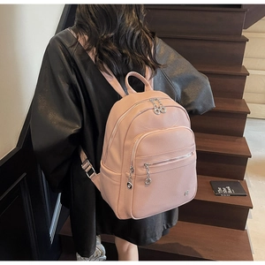 Detailed back view of pink lychee pattern backpack with silver zippers on a model