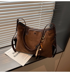 Detail of vintage brown suede tote bag with leather trim and decorative beaded pendant