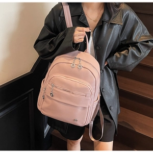 Pink pebbled leather backpack shown on a model in a urban lifestyle setting