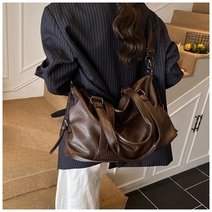 Detail of soft brown PU leather tote bag with silver buckle and thick strap