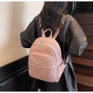 Close-up of pink lychee grain PU leather backpack showing zipper pockets and metal pullers
