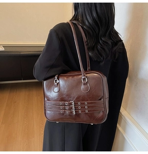 Close-up of a vintage dark brown tote bag with decorative straps and silver buckles