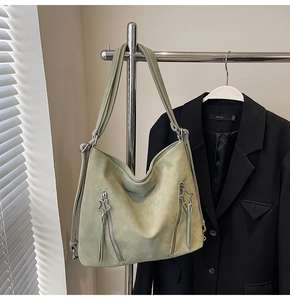 Close-up of light green suede tote bag with silver star-shaped zipper detail