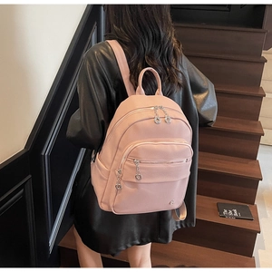 Rear view of a pink pebbled leather backpack featuring multi-pocket design on stairs