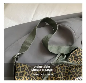 Detail showing adjustable olive green strap and silver buckle on leopard tote bag