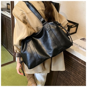 Detailed view of the black oversized tote bag showing smooth leather texture and wide strap