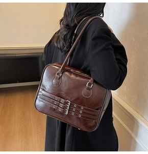 Detail of dark brown glossy leather tote bag with triple buckle and silver hardware