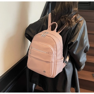 Detail of pink pebbled leather backpack showing silver zippers and functional compartments