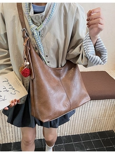 Brown vintage faux leather hobo bag with adjustable strap and decorative fur pompom
