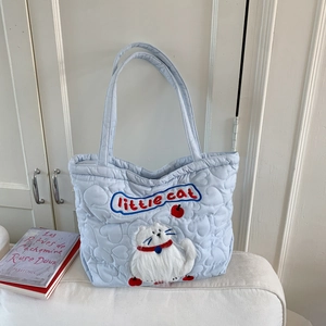 Detail of light blue quilted tote bag with heart patterns and plush cat embroidery