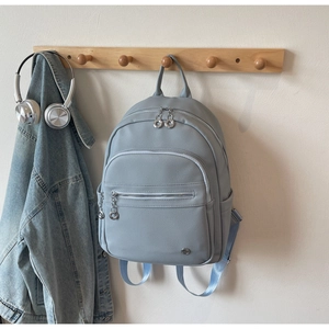 Detail of light blue backpack with lychee texture and silver hardware on a wooden hanger