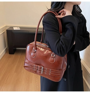 Detail of vintage caramel leather shoulder bag with decorative triple buckle straps