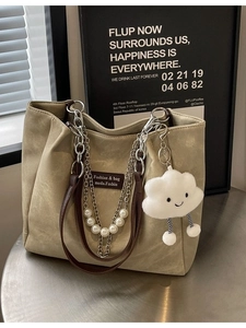 Khaki Shopper mit Silberkette, weißen Perlen und Wolkenanhänger auf einem Tisch
