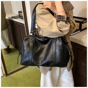 Close-up of black soft leather tote bag with sturdy handles on a model's shoulder