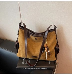 Detail of ginger suede tote bag with dark brown leather straps and wooden bead charm