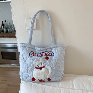 Close-up of light blue quilted tote bag with heart pattern and cat embroidery detail