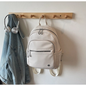 Detail of off-white lychee texture backpack with silver hardware and multi-pocket design