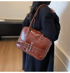 Detail of vintage brown tote bag with triple metal buckle straps on glossy leather