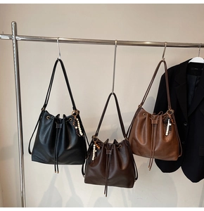 Close-up of three pleated bucket bags in black and brown with wooden bead charms