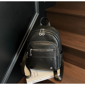 Detail of black pebbled leather backpack with silver zippers and multi-compartment design