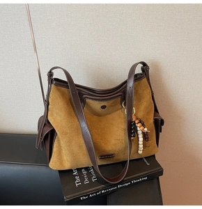 Close-up of yellow suede tote bag with brown leather details and bead pendant