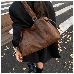 Detail of vintage brown leather tote bag showing texture and wide shoulder strap