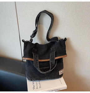Detail of black vintage denim tote bag with leather trim and adjustable shoulder strap