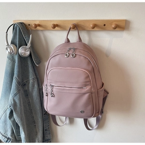 Close-up of pink faux leather backpack with litchi texture hanging on a wooden hook