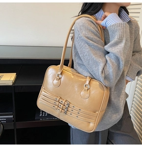 Detail of light brown retro tote bag with triple decorative buckles and silver hardware